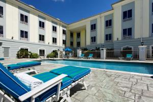 une piscine avec des chaises longues et un hôtel dans l'établissement Holiday Inn Express Trincity, an IHG Hotel, à Piarco