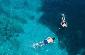 two people swimming in the water in the ocean at KEROMOUSSI SEASIDE BOUTIQUE HOTEL - Adult only in Meganisi