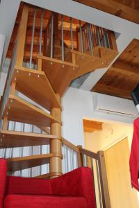 a wooden spiral staircase in a living room with a red couch at Villa Rosa in Moniga