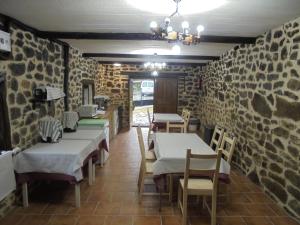 a restaurant with tables and chairs and stone walls at Albergue Areitz Soroa in Arce
