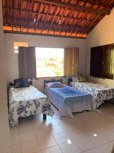 Casa de praia em Carapibus في جاكوما: غرفة نوم بسريرين ونافذة كبيرة