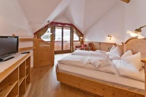 a bedroom with a large bed and a television at Hotel Villa Monica in Dobbiaco