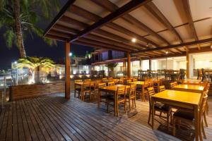 a restaurant with tables and chairs on a deck at night at Castellammare Bombinhas Flat Residence in Bombinhas