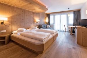 um quarto com uma cama grande e uma secretária em Hotel Villa Monica em Dobbiaco