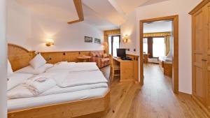 a bedroom with a bed and a desk and a television at Hotel Villa Monica in Dobbiaco