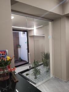 Una ducha de cristal en una habitación con plantas. en Ottomood Ala Ovest Catania Centro, en Catania
