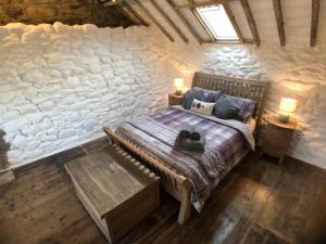 a bedroom with a bed in a stone wall at Gellibant Cottage in Llanbedr