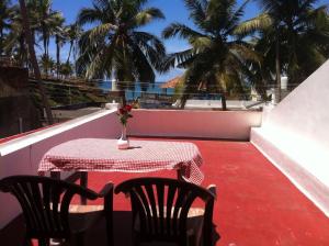 d'une table et de chaises sur un balcon avec des palmiers. dans l'établissement Hotel Samudra Tara, à Kovalam
