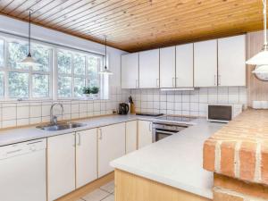 ブラーバンドにある8 person holiday home in Bl vandの白いキャビネットと木製の天井が備わるキッチン