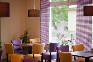 ein Esszimmer mit Tischen, Stühlen und einem Fenster in der Unterkunft Cafe Hehrlich - Cafe, Pension & mehr in Bad Tennstedt