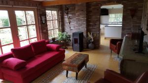 uma sala de estar com um sofá vermelho e uma mesa em De Ketse Steenuil em Kaatsheuvel