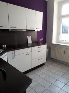 a kitchen with white cabinets and a purple wall at Südvorstadt in Zittau