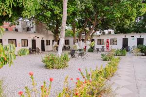 un patio con sillas, mesas y árboles en Hotel Cuchara de Palo Ayenda, en Santa Marta