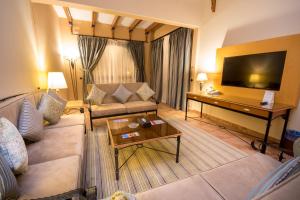 a living room with a couch and a television at Mena Holiday Beach Resort Half Moon in Half Moon Bay