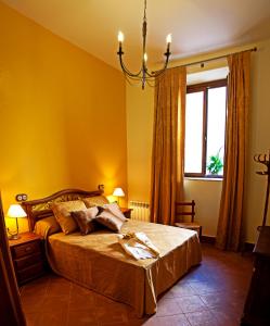 a bedroom with a bed with yellow walls and a chandelier at Hotel Rural El Salero in Torija