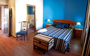 1 dormitorio azul con 1 cama y 1 silla en Hotel Rural El Salero, en Torija