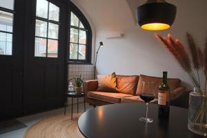 a living room with a couch and a table with a wine glass at Overnachten in de oude West-Indiëschool in Enschede