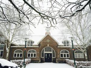 un gran edificio de ladrillo con nieve en el suelo en Overnachten in de oude West-Indiëschool, en Enschede