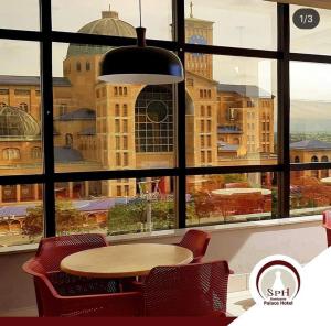 a table and chairs in front of a large window at Santuário Palace Hotel in Aparecida