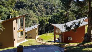 a view of two houses with trees in the background at Robinson Cottage Monte Verde MG in Monte Verde