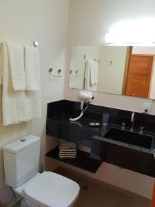 a bathroom with a white toilet and a sink at Robinson Cottage Monte Verde MG in Monte Verde
