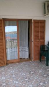 a room with two sliding glass doors and a green chair at Apartments Kuss in Novalja