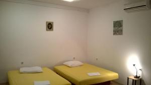 two twin beds in a room with yellow sheets at Apartments Kuss in Novalja