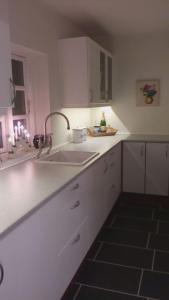 a kitchen with a sink and white cabinets and a window at Hos Anna in Roskilde