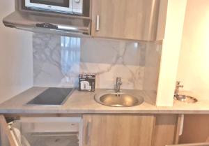 a kitchen counter with a sink and a microwave at CARO Boutique Guest House in San Ġwann