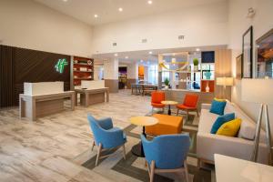 an office lobby with chairs and a couch and tables at Holiday Inn Pensacola - University Area, an IHG Hotel in Pensacola