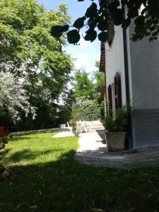 einen grünen Hof mit einem Gebäude, Bäumen und Gras in der Unterkunft Da Marisetta a San Severino Marche in San Severino Marche