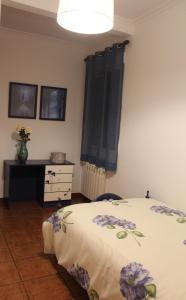 CASA RURAL BUENA VENTURA في فيلانيوفا دي لوس إنفانتس: غرفة نوم مع سرير مع زهور أرجوانية عليه