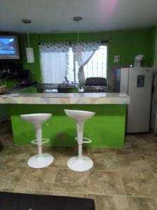 a green kitchen with two stools in front of a counter at Villa mar in Puerto Colombia