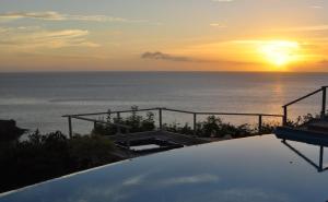 a sunset over the ocean with the sun setting on the horizon at Infiniti Blue in Bouillante