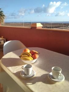 un bol de fruta sentado en una mesa con dos tazas en REGINA VITTORIA, en La Oliva
