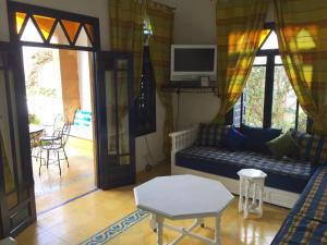 a living room with a couch and a tv at Villa Jardins de la Lagune in Oualidia