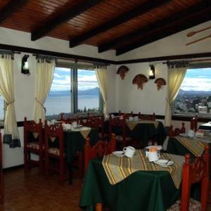 ein Restaurant mit grünen Tischen, Stühlen und Fenstern in der Unterkunft Ruca Cheli Village Ski Hotel in San Carlos de Bariloche