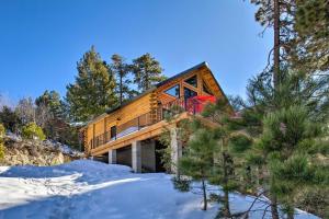 a wooden house with a red door in the snow at Luxury Mountain Cabin with Furnished Deck and Views! in Loma Linda