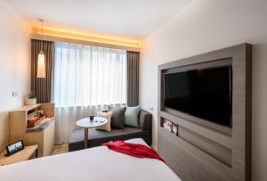 a hotel room with a bed and a large flat screen tv at ibis Melbourne Central in Melbourne