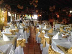 una habitación llena de mesas blancas con arcos amarillos en Hotel Casablanca Natural Spa, en Paipa