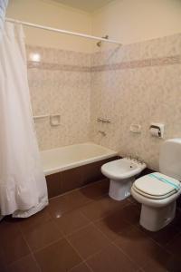 a bathroom with a tub and a toilet and a sink at Hotel Bahía in Puerto San Julian