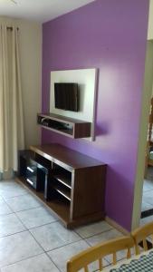 sala de estar con pared morada y TV en Residencial Caxias, en Bombinhas