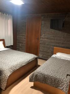 Un dormitorio con dos camas y una pared de ladrillo. en Chalés De Luxe Gramado, en Gramado