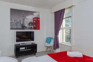 a bedroom with a bed and a tv and a window at Windsor House in Derry Londonderry