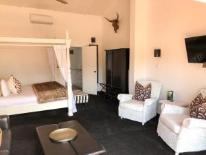 a living room with a bed and two chairs at Orewa Beachcomber in Orewa