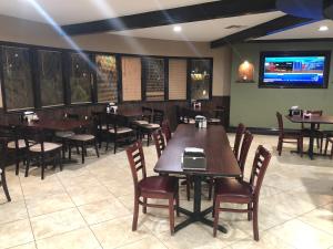 a restaurant with tables and chairs and a flat screen tv at Royal Inn in Port Lavaca