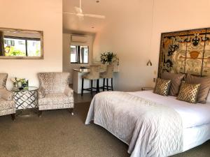 a bedroom with a large bed and two chairs at Orewa Beachcomber in Orewa