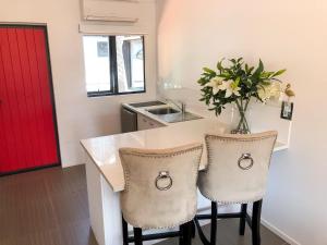 a kitchen with two chairs and a table with a vase of flowers at Orewa Beachcomber in Orewa