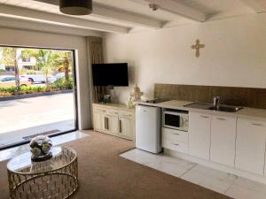 a kitchen with white appliances and a large sliding glass door at Orewa Beachcomber in Orewa