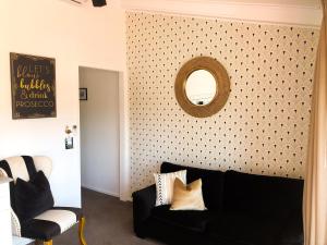 a living room with a black couch and a mirror at Orewa Beachcomber in Orewa